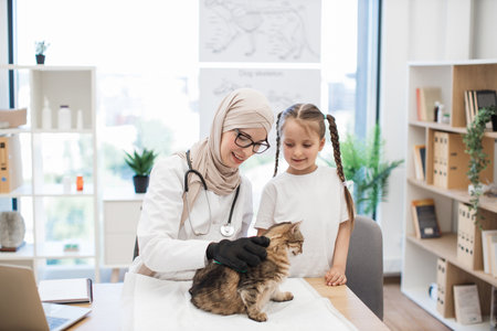 Vet doctor teaching girl care tips with pet grooming gloveの写真素材