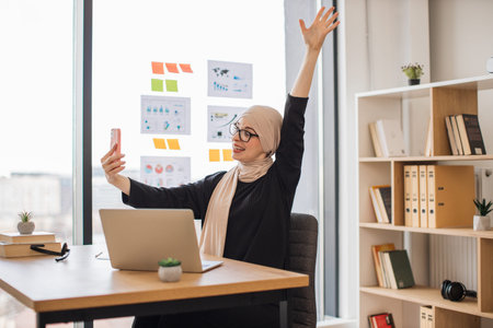 Lady enjoying news on online chat with teammates at workの写真素材