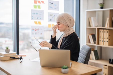 Female employee easing pain in nose during office workの写真素材
