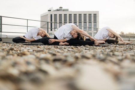 Females practicing deep stretch in outside yoga sessionの写真素材