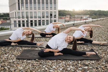 Adults posing in side stretch during outdoor workout on roofの写真素材