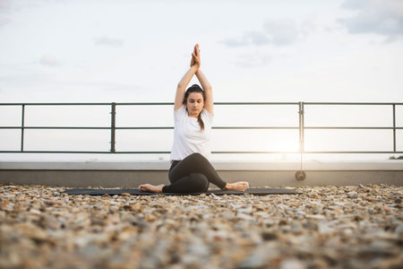 Adult meditating in pose with twisted legs on gravel roof