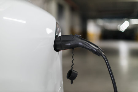 E-car back part with charging cord in port in parking lot