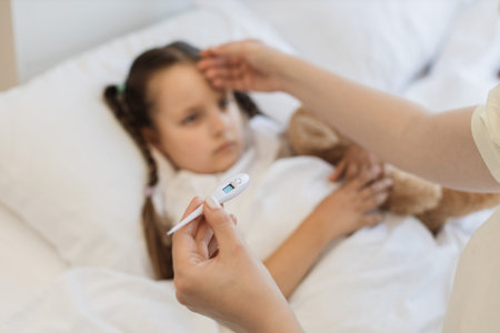 Mother using thermometer for checking fever of sick girl