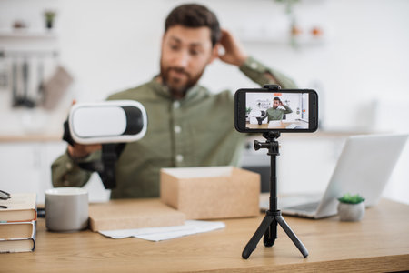 Male showing virtual reality glasses and filming on mobileの写真素材