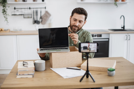 Smartphone filming video of man doing unpacking of laptopの写真素材