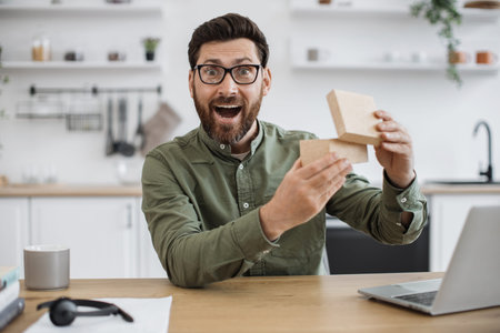 Man experiencing pleasant shock while unpacking parcel box