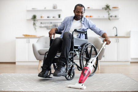 Man with mobility impairment housekeeping with stick vacuumの写真素材