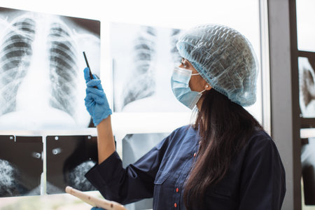 Female worker posing with digital tablet near x-ray scans