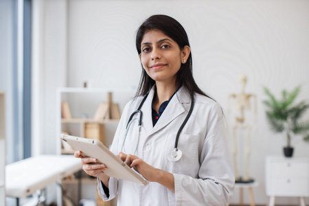 Therapist holding tablet while posing in doctors office