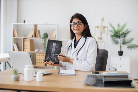 Female physician pointing at x-ray on tablet at workplaceの写真素材