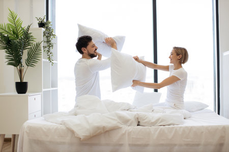 Young passionate Caucasian couple fighting with pillowsの写真素材