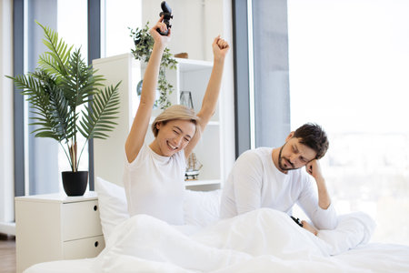 Caucasian couple in love have fun competing in laptop game using joysticksの写真素材
