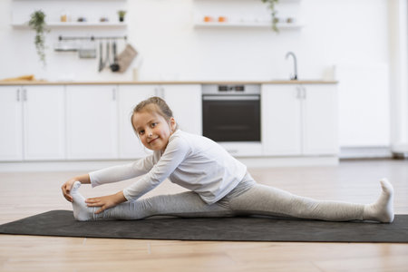 Girl in white sports wear makes stretching training doing splits exercise.の写真素材