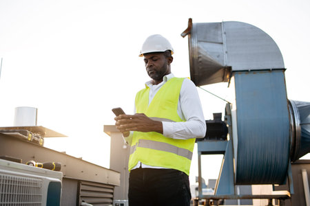 Construction man standing and typing on mobile on roof