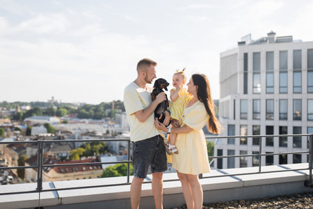 Pleased family and dog standing together on roof of buildingの写真素材