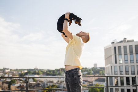 Male raising up his dog and kissing on city backgroundの写真素材