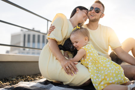 Couple sitting together while baby hugging dog on local roofの写真素材
