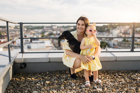 Smiling mother hugging infant while black dog sitting on lapの写真素材