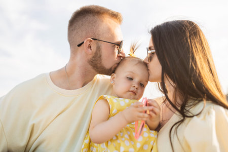 Young parents with dog holding and kissing baby on balconyの写真素材