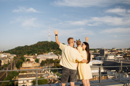 Lovely family of three standing on roof with view of cityの写真素材