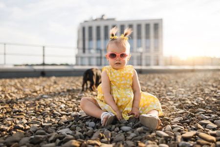 Small stylish girl sitting with dog on rocky path of rooftopの写真素材