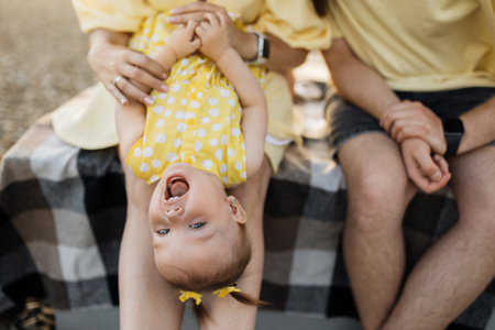 Parents playing with daughter on open area during sunsetの写真素材