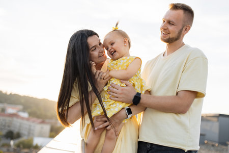 Parents embracing daughter and smiling on high-rise terraceの写真素材