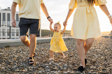 Close up of parents holding child hands walking on terraceの写真素材