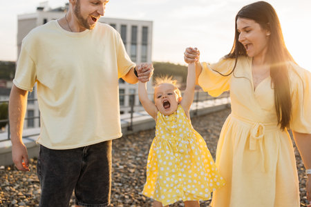 Family of mom, dad and daughter playing with dog on rooftopの写真素材