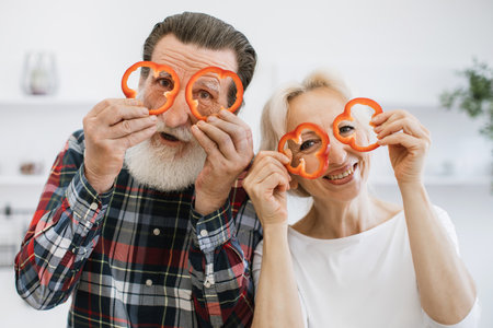 Elderly couple, husband and wife, having fun in kitchen while preparing breakfast.の写真素材