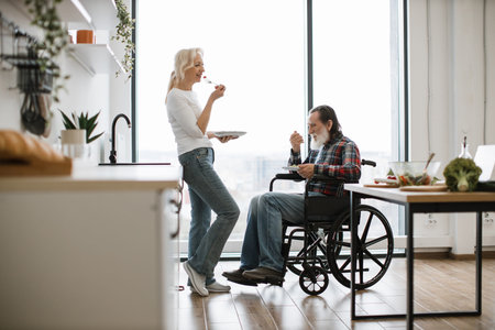 Elderly couple, husband in wheelchair and wife, eating fresh healthy salad.