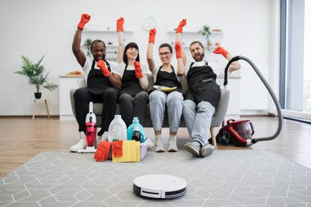 Robot vacuum cleaner cleans floor while team of housekeepers raising hands.の写真素材