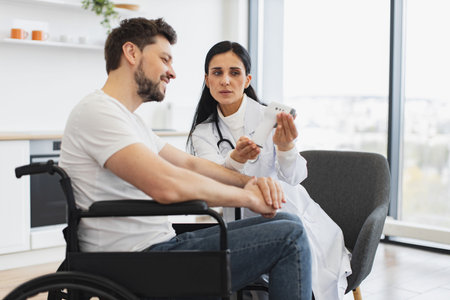 Woman doctor or nurse, visiting her mature male patient with disability at home.の写真素材