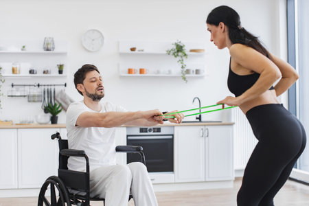 Physiotherapist in sportswear helping male patient in wheelchair exercise.