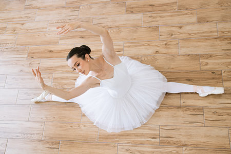 Top view of professional caucasian ballerina in white tutu and pointe stretchingの写真素材