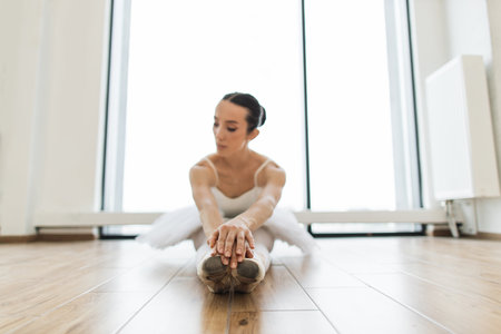 Portrait of young woman ballerina sitting on the wooden floor in dance club.の写真素材