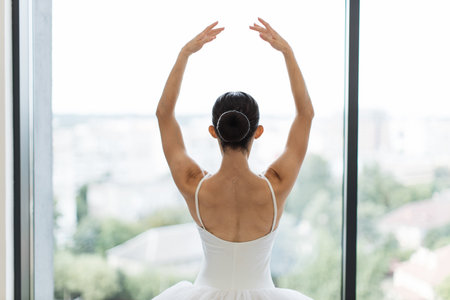 Female ballet dancer makes pirouette at ballet studio in front of big window.の写真素材