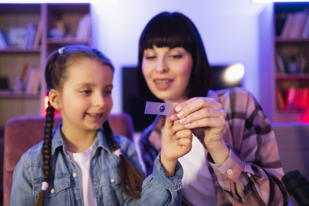Young woman teaching girl to make biological research at evening home.の写真素材