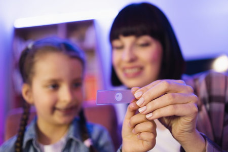 Young woman teaching girl to make biological research at evening home.