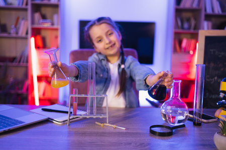 Caucasian girl scientist sitting at table playing with chemistry equipment.