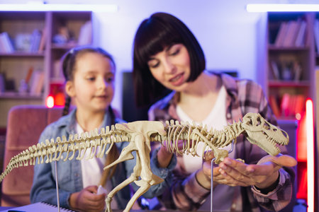 Two female sitting together at table and make model of tyrannosaurus.の写真素材