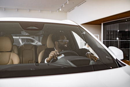 Calm African man customer buyer client in suit holding hands on steering wheel.