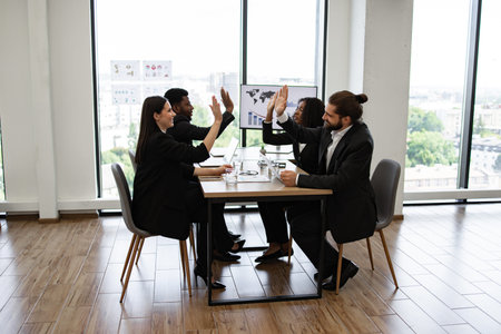 Successful business team celebrating with high fives in office meeting