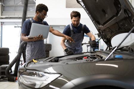 Auto mechanics working together in garage with laptopの写真素材