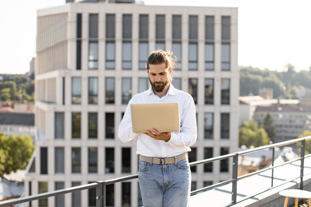 Young professional working on laptop on rooftop terraceの写真素材