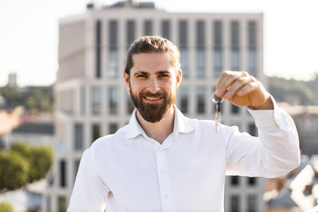 Smiling man holding keys to new apartment in city