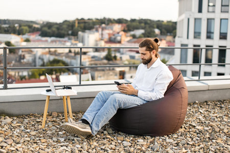Businessman working remotely on rooftop with city viewの写真素材