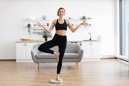 Woman practicing yoga and balancing on one foot at homeの写真素材