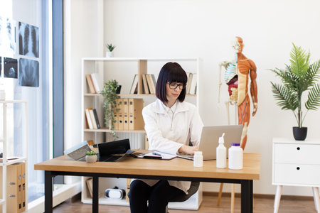 Female doctor working on laptop in modern medical office